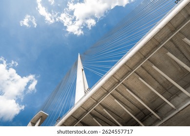 Low angle view of the Ada bridge in Belgrade, Serbia, highlighting its modern architecture against a vibrant blue sky