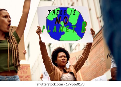 Low angle view of African American woman carrying banner with there is no planet B inscription while protesting with crowd of activists against climate changes. - Shutterstock ID 1773660173