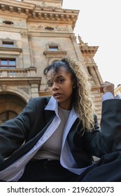 Low Angle View Of African American Woman Listening Music In Wireless Earphone Near National Theatre In Prague