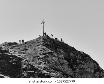 Low angle view of alpine peak with huge summit cross and group of hikers against the clear sky       