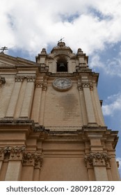 Low angle view of an ancient cathedral belfry with clock against blue sky and clouds.