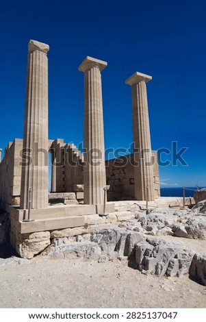 Low angle view of ancient Doric stone columns rising against a blue sky in Greece.