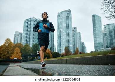 Low angle view of athlete jogging while having sports training outdoors during rainy day. Copy space.  - Powered by Shutterstock