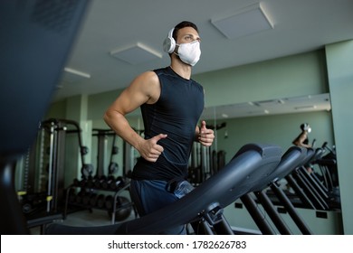 Low angle view of athletic man wearing protective face mask while running on treadmill in a gym.  - Powered by Shutterstock