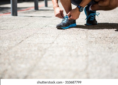 Low Angle View Of An Athletic Man Tying His Shoe Laces