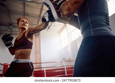 Low angle view of athletic woman practicing boxing with a coach in health club. Copy space.  - Powered by Shutterstock
