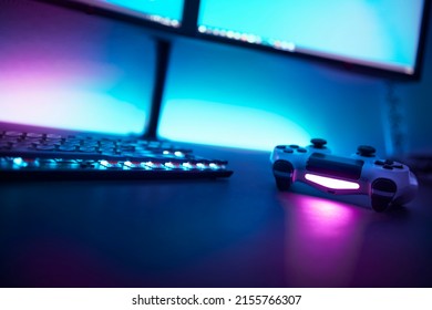 Low angle view of backlighted keyboard and game controller on table. Light blue illuminated wall in background. Professional computer game playing, esport business and online world concept. - Powered by Shutterstock