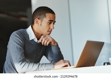 Low Angle View Of A Black Businessman Working On A Laptop Computer Concentrating On His Work In Side View