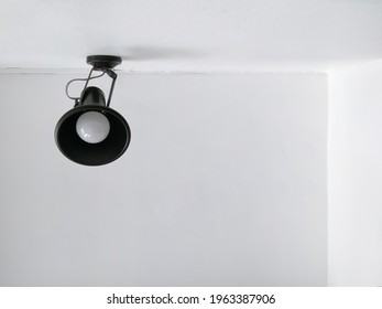 Low Angle View Of Black Modern Wall Lamp On White Cement Wall With Ceiling In Home Office Room