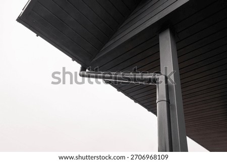 Low angle view of black rain gutter system on wooden roof soffit