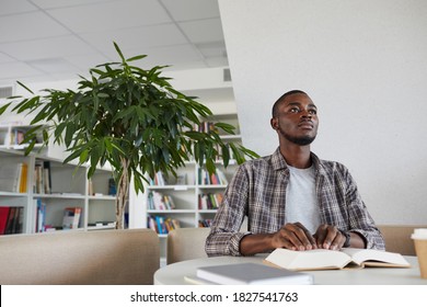 Low angle view at blind African-American man reading Braille book in school library, copy space - Powered by Shutterstock