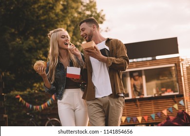 low angle view of boyfriend feeding girlfriend with french fries near food truck - Powered by Shutterstock