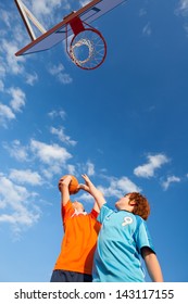Low angle view of boys playing basketball against sky