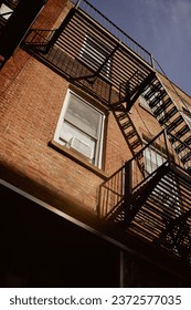 low angle view of brick building with fire escape stairs in new york city, urban architecture