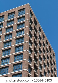 Low angle view of a brown brick wall building exterior with windows against blue sky background.