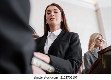 Low Angle View Of Brunette Witness Giving Oath On Bible In Court