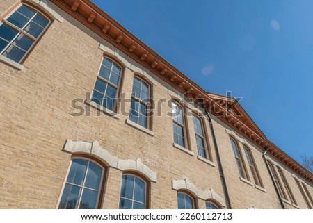 Low angle view of a building with bricks and paned windows in Austin, Texas. Building exterior with brown roof dentils against the clear blue skies.