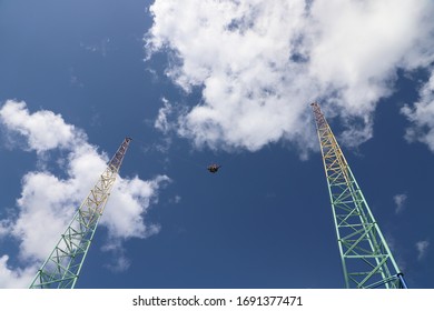 Low Angle View Of Bungee Slingshot Amusement Park Ride With Clouds And Blue Sky