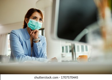 Low angle view of businesswoman with face mask working on desktop PC in the office.  - Powered by Shutterstock