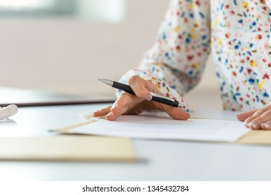 Low angle view of businesswoman at her office desk proofreading a document or contract in a paper folder before signing it.