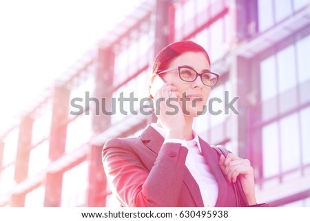 Low angle view of businesswoman using cell phone outside office building