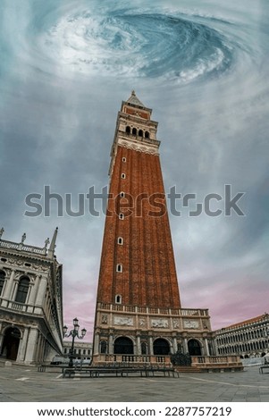Low angle view of the Campanile bell tower on St. Mark's square in center of Venice under dramatic cloudy sky with huge storm vortex, Italy. Scary apocalyptic scene