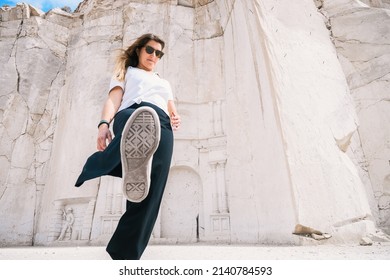 Low angle view of a caucasian woman showing her sole while visiting the great stone wall of Petra in Sillar's route, Arequipa, Peru. Horizontal. With copy space. Kick concept.
