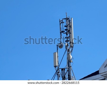 Low angle view of cellular telecommunication tower with antennas and transmitters against clear blue sky.