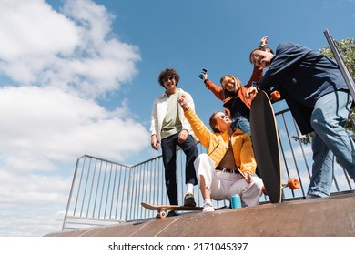 low angle view of cheerful multiethnic friends on skate ramp against blue cloudy sky - Powered by Shutterstock