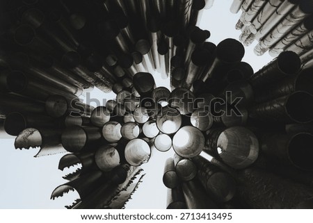 Low Angle View of Circular Metal Pipes Forming Abstract Cylindrical Structure Against Bright Sky