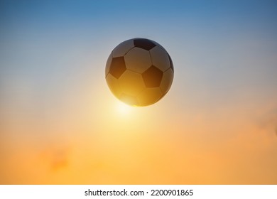 Low Angle View Of Classic Black And White Ball Or Soccer Football Flying In Twiligth Sky. Sport Game And Athlete Concept With No People.