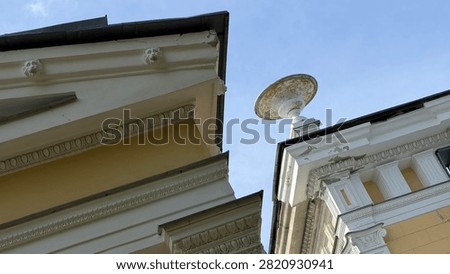Low angle view of classic neoclassical facade with decorative urn sculpture and lion head reliefs.