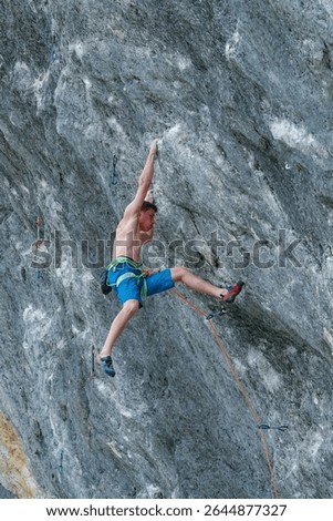 LOW ANGLE VIEW, CLOSE UP: Agile male climber moves up a challenging rock face. Focused young man shows incredible power and determination while overcoming a difficult section on a French climbing site