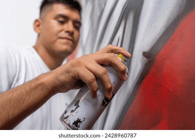 Low angle view close-up of a young male latin muralist painting a wall using spray - Powered by Shutterstock