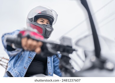 Low angle view of a concentrated hispanic young adult woman wearing helmet driving a motorcycle