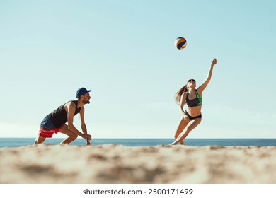 Low angle view. Concentrated young man and woman in sportswear in motion, play in beach volleyball under sunny clear sky. Concept of sport, summer, nature, active lifestyle, youth - Powered by Shutterstock