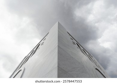 Low angle view of the corner of Sheikh Zayed Grand Mosque, Solo against cloudy sky background. The corner of a large, white building with a geometric design. Grandeur architectural background.