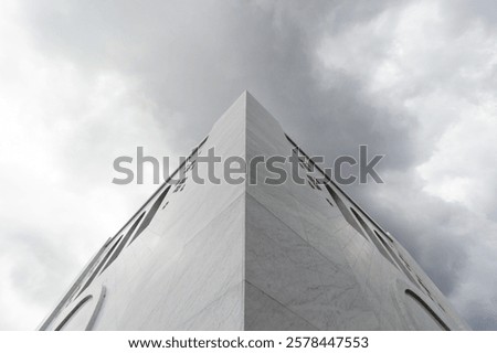 Low angle view of the corner of Sheikh Zayed Grand Mosque, Solo against cloudy sky background. The corner of a large, white building with a geometric design. Grandeur architectural background.