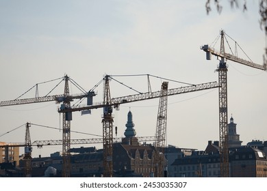 Low angle view of cranes above the city