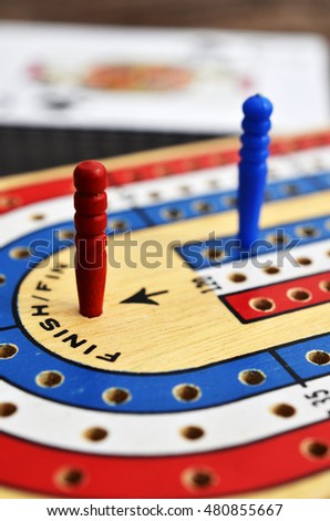 A low angle view of a cribbage board with a red cribbage peg in the winning position.