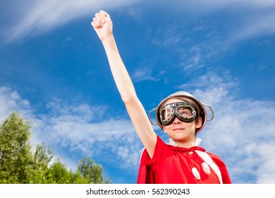 Low Angle View Of Cute Teen Boy Wearing Metal Colander As A Helmet Goggles And Red Costume - A Funny Power Super Hero Child Concept