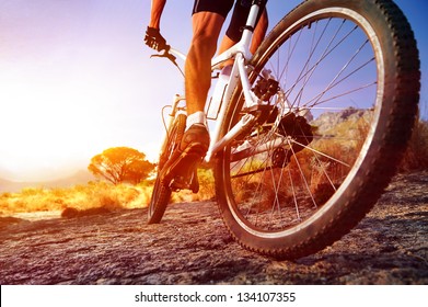 low angle view cyclist riding mountain bike rocky trail at sunrise