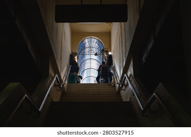 Low angle view of dark staircase leading to bright arched exit