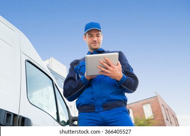 Low angle view of delivery man using digital tablet by truck against sky - Powered by Shutterstock