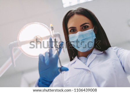 low angle view of dentist in medical mask holding syringe in modern dental clinic