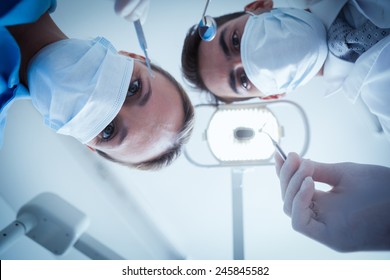 Low angle view of dentists in surgical masks holding dental tools