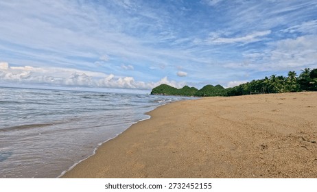 Low angle view of a deserted beach with islands in the distance under a blue sky in Sugar Beach in Sipalay, Negros Occidental, Philippines