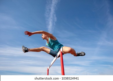 Low angle view of determined male athlete jumping over a hurdles