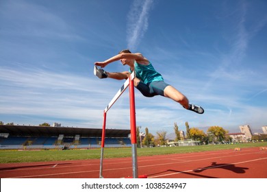 Low angle view of determined male athlete jumping over a hurdles