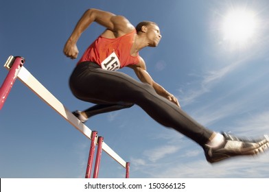 Low Angle View Of Determined Male Athlete Jumping Over A Hurdles